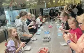 Na zdjęciu dzieci pracujące nad tworzeniem ozd&oacute;b choinkowych lub oglądających gotowe ozdoby