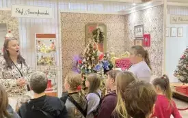 Na zdjęciu dzieci pracujące nad tworzeniem ozd&oacute;b choinkowych lub oglądających gotowe ozdoby