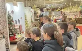 Na zdjęciu dzieci pracujące nad tworzeniem ozd&oacute;b choinkowych lub oglądających gotowe ozdoby