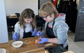 Na zdjęciu osoby, dzieci i dorośli, podczas warsztat&oacute;w kulinarnych