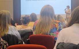 Na zdjęciu osoby w eleganckiej sali konferencyjnej