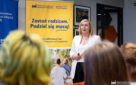 Na zdjęciu grupa os&oacute;b w trakcie spotkania w pomieszczeniu z projektorem i plakatami