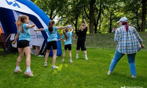 Na zdjęciu niebieski dmuchany namiot w przestrzeni miejskiej oraz osoby znajdujące się wokół