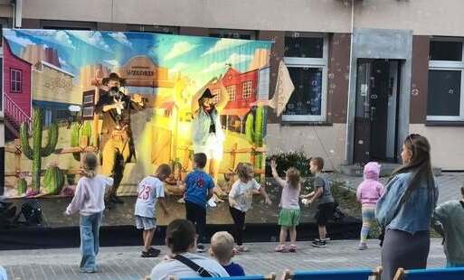 Na zdjęciu dorośli i dzieci bawiący się podczas plenerowej imprezy